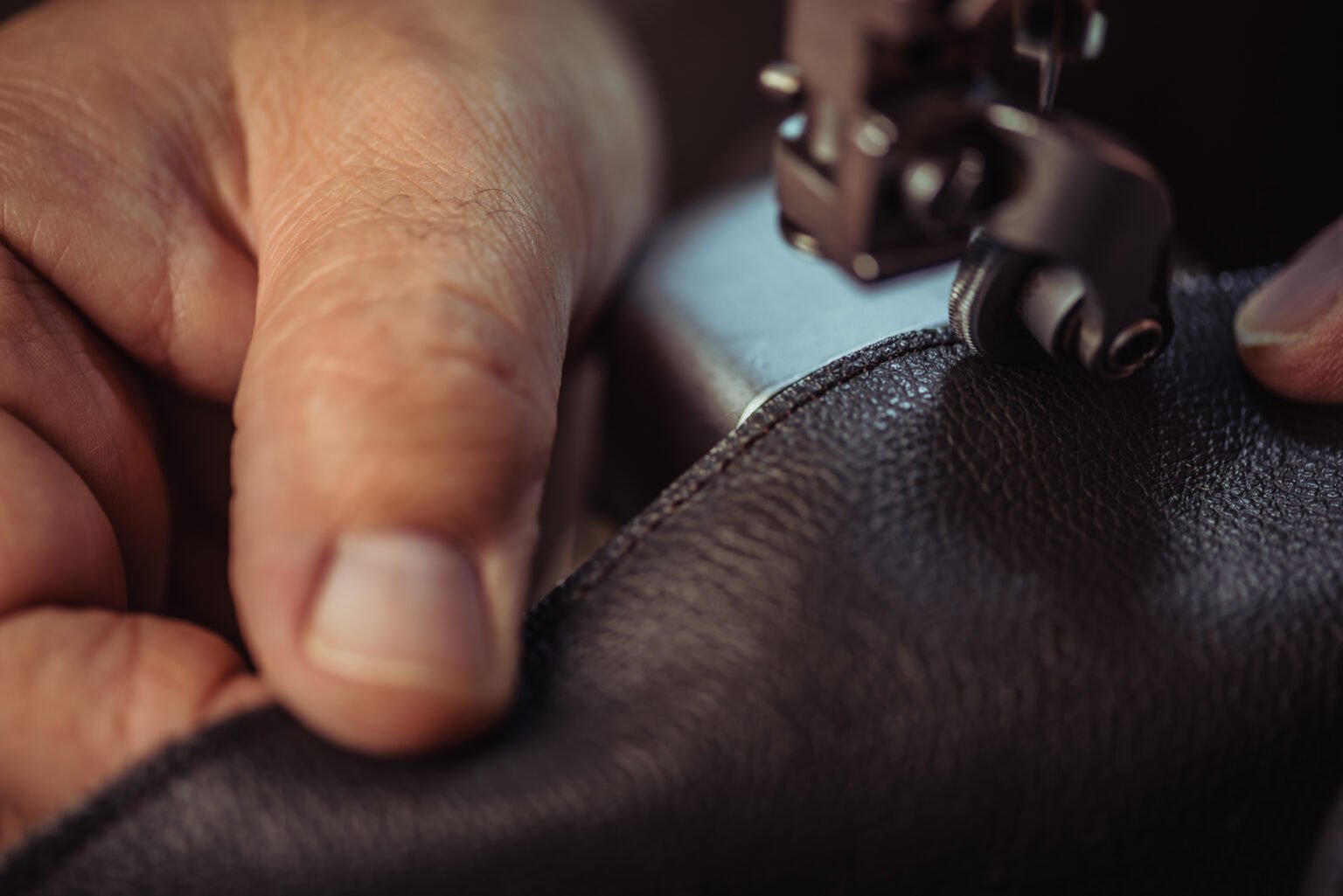 Genuine leather material being upholstered by hand using a sewing machine.