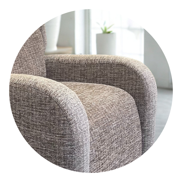 Close-up of a chair's upholstered scroll arm with a subtle patterned fabric, highlighting its elegant curve.